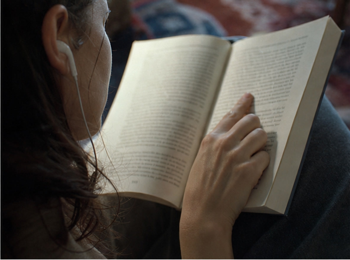 Close-up of a hand following text in an open book