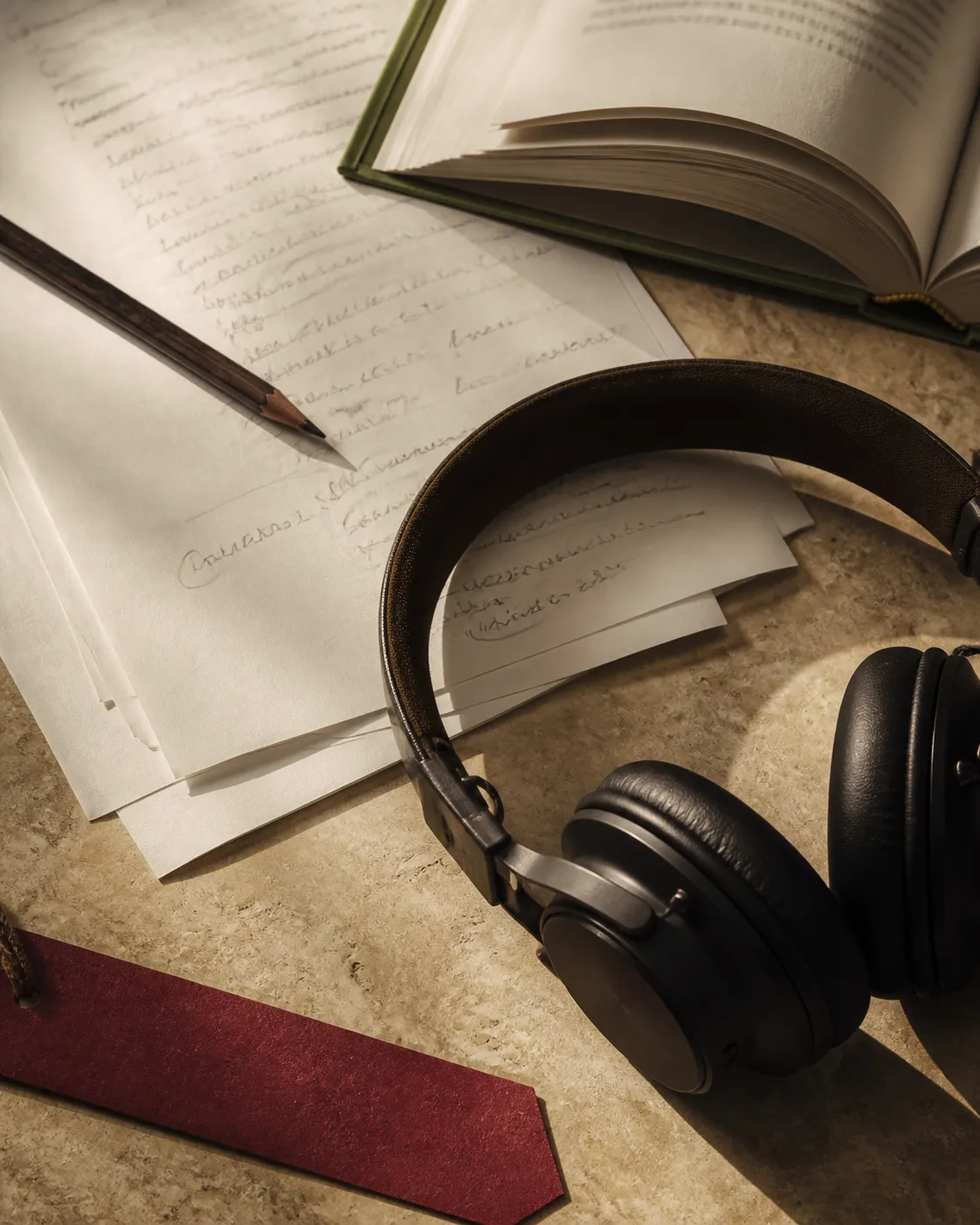 Printed pages, a book, and headphones in warm window light